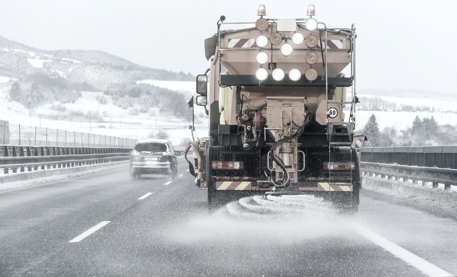 Snow plow on highway salting road.