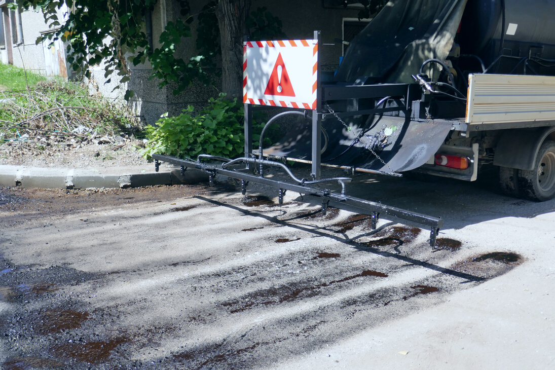 Oil spreader truck applying tack coats spraying bitumen emulsion with  spray lance before applying a new layer of asphalt